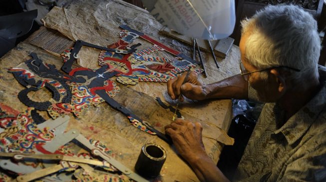 Perajin wayang, Mertowirejo (81) menyunging (melukis) wayang kertas sintetis dengan cat minyak di Solo, Jawa Tengah, Sabtu (7/3). [ANTARA FOTO/Maulana Surya]