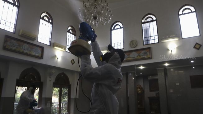 Petugas menyemprotkan cairan disinfektan di Masjid Nurul Hidayah, Jalan Brawijaya XII, Jakarta Selatan, Minggu (8/3). [Suara.com/Angga Budhiyanto]