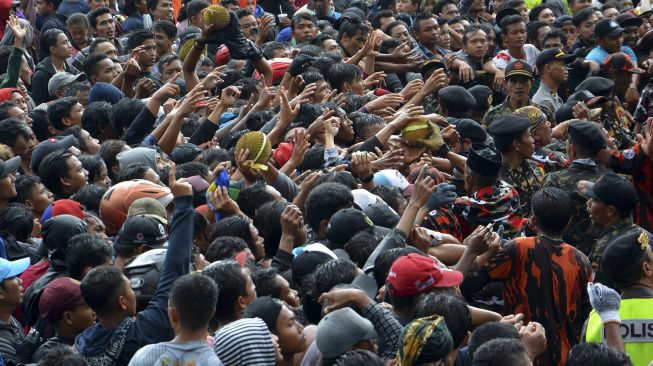 Pengunjung berebut buah durian saat pesta durian atau Kenduren di Lapangan Wonosalam, Kabupaten Jombang, Jawa Timur, Minggu (8/3). [ANTARA FOTO/Syaiful Arif]