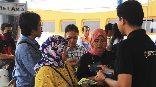 Sejumlah wanita pekerja migran yang dideportasi dari Malaysia menyerahkan dokumen perjalanan menyerupai paspor kepada petugas perlindungan tenaga kerja di Pelabuhan Internasional PT Pelindo I Dumai di Dumai, Riau, Sabtu (7/3). [ANTARA FOTO/Aswaddy Hamid]