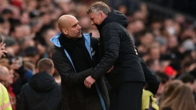 Manajer Manchester City Josep Guardiola memberikan selamat kepada manajer Manchester United Ole Gunnar Solskjaer usai pertandingan Liga Inggris yang berakhir 2-0 bagi tuan rumah di Old Trafford, Minggu (8/3/2020). [AFP]