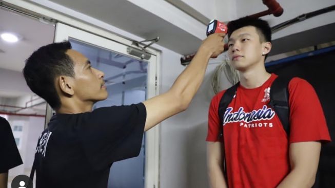 Pemain Tim nasional basket Indonesia, Vincent Rivaldi Kosasih melewati pemeriksaan suhu tubuh sebelum memasuki venue seri VI IBL 2020 tepatnya di DBL Arena, Surabaya. [Dok. Instagram@IBLIndonesia]