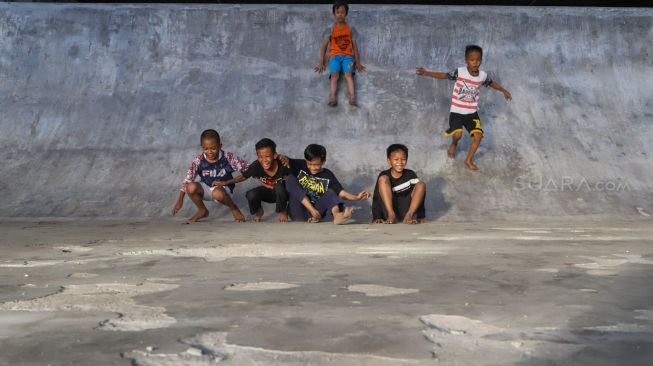 Anak-anak bermain perosotan di area Skate park Fly Over Slipi, Jakarta Pusat, Senin (9/3). [Suara.com/Alfian Winanto]
