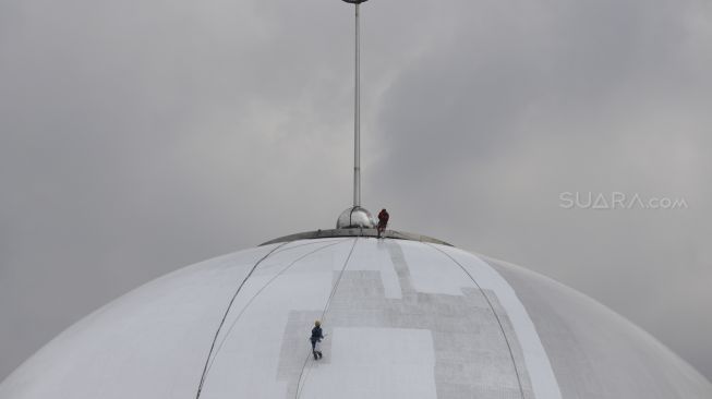 Sejumlah pekerja dengan pengaman lengkap melakukan pengecatan pada bagian kubah Masjid Istiqlal, Jakarta, Selasa (10/3).  [Suara.com/Angga Budhiyanto]