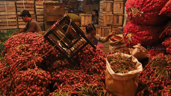 Pedagang membersihkan bawang merah di Pasar Induk Kramat Jati, Jakarta Timur, Selasa (10/3). [Suara.com/Alfian Winanto]