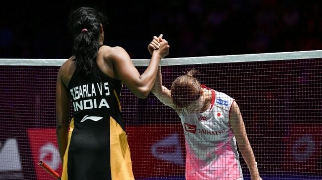 Tunggal putri India, Pusarla V. Sindhu (kiri), berjabat tangan dengan Nozomi Okuhara (Jepang) usai memenangi final Kejuaraan Dunia Bulutangkis 2019 di St. Jakobshalle Basel, Swiss, Minggu (25/8). [AFP/Fabrice Coffrini]