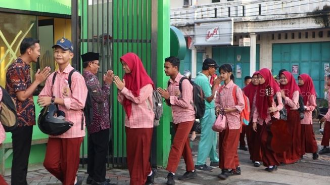 Sekolah di Surabaya merubah cara salaman dengan siswanya untuk antisipasi penyebaran virus corona. (Suara.com/ Achmad Ali)