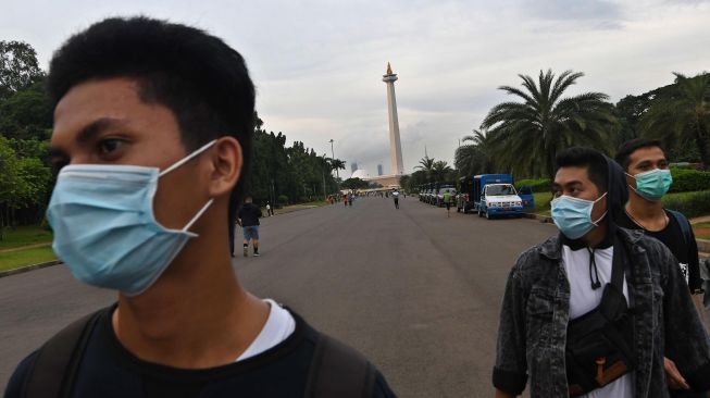 Warga dengan menggunakan masker berjalan di kawasan Monumen Nasional, Jakarta, Rabu (11/3). [ANTARA FOTO/Aditya Pradana Putra]