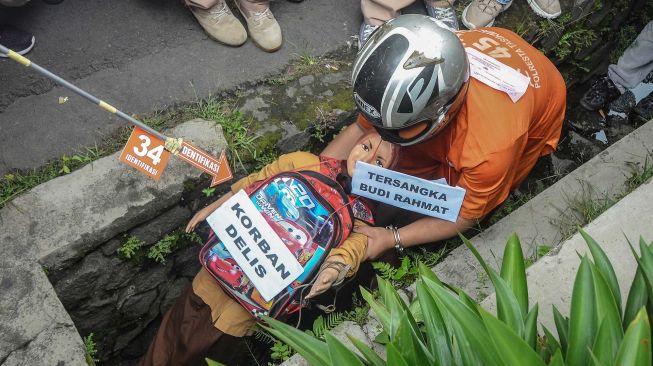 Tersangka Budi Rahmat memasukan korban ke gorong-gorong saat reka ulang pembunuhan kepada anaknya sendiri pada rekontruksi di Cilembang, Kota Tasikmalaya, Jawa Barat, Kamis (12/3). [ANTARA FOTO/Adeng Bustomi]