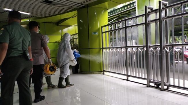 Petugas saat melakukan penyemprotan disinfektan di Stasiun Gambir, Jakarta Pusat. (Suara.com/Ria Rizki).