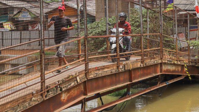 Pengguna JPO berlari karena motor dibelakangnya saat melintasi JPO (Jembatan Penyeberangan Orang) yang ada di Jl. KH. Noer Ali, Kalimalang, Bekasi, Kamis (12/3). [Suara.com/Alfian Winanto]