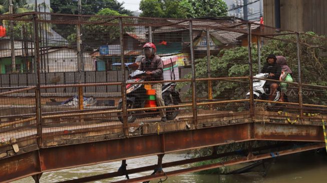 Pengendara motor melewati JPO (Jembatan Penyeberangan Orang) yang ada di Jl. KH. Noer Ali, Kalimalang, Bekasi, Kamis (12/3). [Suara.com/Alfian Winanto]
