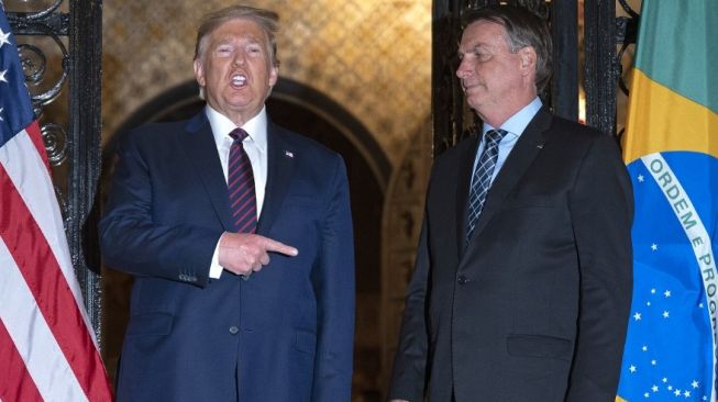 Presiden AS, Donald Trump (kiri) dan Presiden Brasil Jair Bolsonaro bertemu jelang makan malam di Florida, AS pada 7 Maret 2020. Bolsonaro disebut sudah terinfeksi virus corona Covid-19. [AFP/Jim Watson]