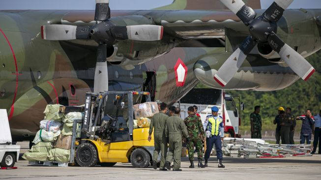 Personel TNI Angkatan Udara dengan menggunakan alat berat menurunkan bahan material yang akan digunakan untuk pembangunan rumah sakit khusus Corona (COVID-19) dari pesawat Hercules C-130 di Bandara Hang Nadim Batam, Kepulauan Riau, Kamis (12/3). [ANTARA FOTO/M N Kanwa]