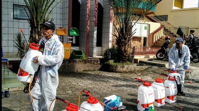 Petugas DMI membawa cairan disinfektan yang akan disemprotkan ke area Masjid Jami Al-Munawwar, Pancoran, Jakarta Selatan, Jumat (13/3/2020). (Suara.com/M. Yasir)