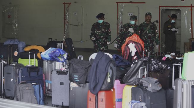 Anggota TNI menyemprotkan cairan desinfektan ke barang-barang milik WNI Anak Buah Kapal (ABK) World Dream tiba di Dermaga Komando Lintas Laut Militer (Kolinlamil), Tanjung Priok, Jakarta Utara, Sabtu (14/3). [Suara.com/Angga Budhiyanto]