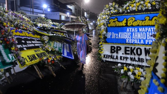 Warga melintasi karangan bunga yang terpasang di rumah duka almarhum Kepala Pusat Pelaporan Analisis dan Transaksi Keuangan (PPATK) Kiagus Ahmad Badaruddin di Tebet, Jakarta, Sabtu (14/3).   [ANTARA FOTO/Aditya Pradana Putra]