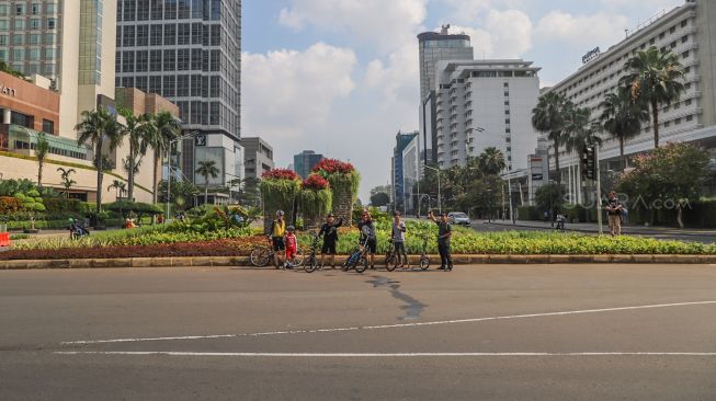 Pesepeda berpose di kawasan Bundaran Hotel Indonesia (HI) di Jalan Sudirman - Thamrin, Jakarta, Minggu (15/3). [Suara.com/Alfian Winanto]