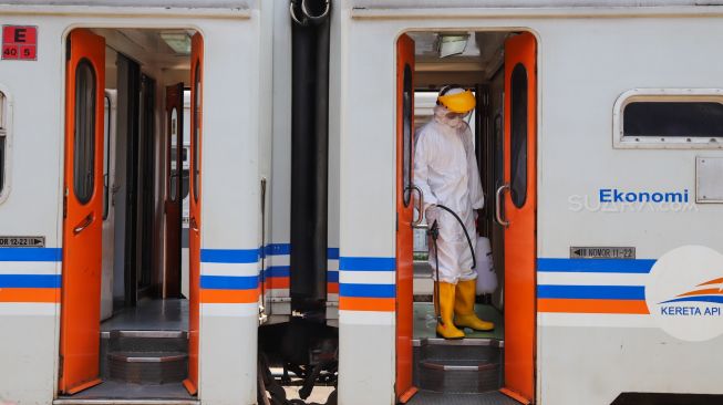 Petugas bersiap menyemprotkan cairan disinfektan di pintu gerbong kereta di Stasiun Pasar Senen, Jakarta, Minggu (15/3).[Suara.com/Alfian Winanto]