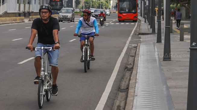 Pesepeda melintasi Jalan Sudirman - Thamrin, Jakarta, Minggu (15/3). [Suara.com/Alfian Winanto]