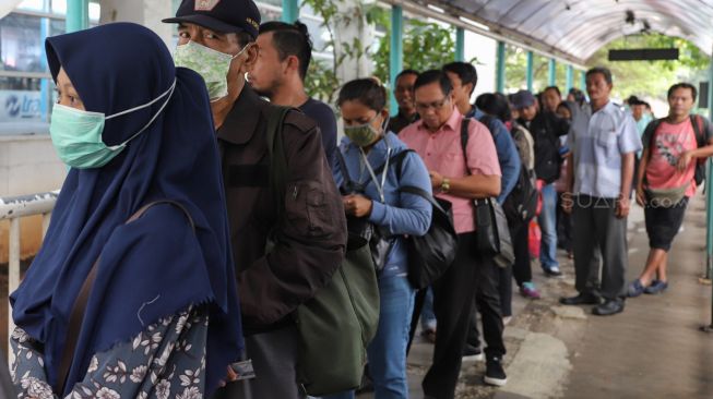 Penumpang Transjakarta mengantre di halte Transjakarta Pinang Ranti, Jakarta Timur, Senin (16/3). [Suara.com/Alfian Winanto]