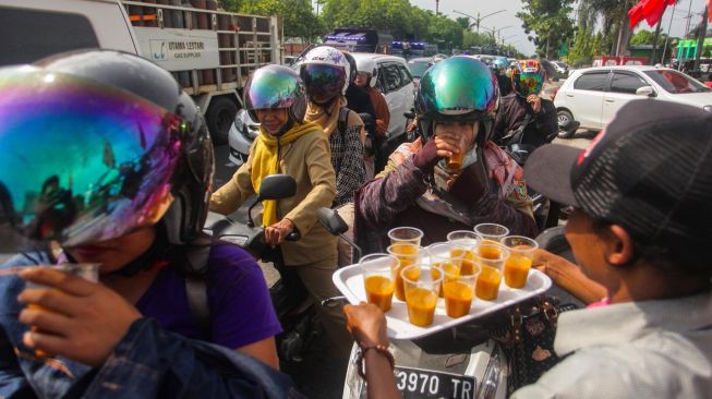 Warga membagikan jamu tradisional secara gratis di Jalan RTA Milono, Palangkaraya, Kalimantan Tengah, Senin (16/3).   [ANTARAFOTO/Makna Zaezar]