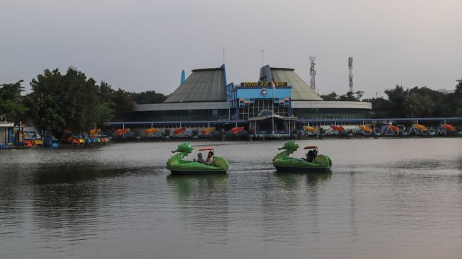 Dua pengunjung menaiki boat wisata di Taman Mini Indonesia Indah, Jakarta Timur, Rabu (18/3). [Suara.com/Alfian Winanto]