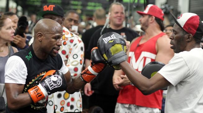 Legenda tinju dunia Floyd Mayweather Jr. (kiri) tengah berlatih bersama paman sekaligus pelatihnya, Roger Mayweather, di Mayweather Boxing Gym, Las Vegas, Amerika Serikat. [AFP/John Gurzinski]