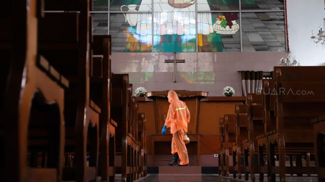 Petugas menyemprotkan disinfektan di dalam Gereja Katolik Santa Catharina di kawasan Taman Mini Indonesia Indah (TMII), Jakarta Timur, Rabu (18/3). [Suara.com/Alfian Winanto]
