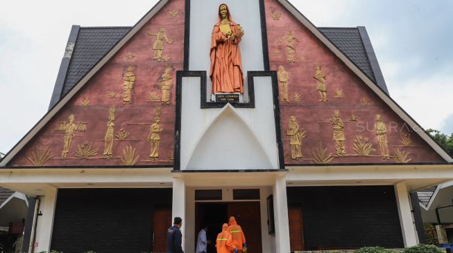 Petugas menyemprotkan disinfektan di pintu masuk Gereja Katholik Santa Catharina di kawasan Taman Mini Indonesia Indah (TMII), Jakarta Timur, Rabu (18/3). [Suara.com/Alfian Winanto]