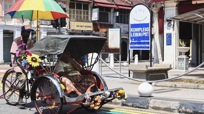 Seorang pengemudi becak membawa penumpang di Penang Malaysia, Rabu (18/3). [GOH CHAI HIN / AFP]
