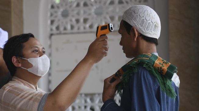 Petugas mengukur suhu tubuh warga sebelum melaksanakan Salat Jumat di Masjid Jami' Arriyadut Taqwa, Jakarta Selatan, Jumat (20/3/2020). [ ANTARA FOTO/Wahyu Putro]