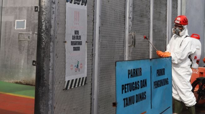 Petugas PMI menyemprotkan cairan disinfektan di gerbang utama Lapas kelas 1 Cipinang, Jakarta Timur, Jumat (20/3). [Suara.com/Alfian Winanto]
