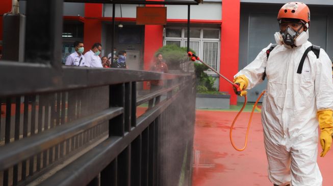 Petugas PMI menyemprotkan cairan disinfektan pagar-pagar di halaman Lapas kelas 1 Cipinang, Jakarta Timur, Jumat (20/3). [Suara.com/Alfian Winanto]