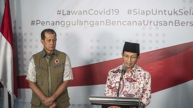 Imam Besar Masjid Istiqlal Nasaruddin Umar didampingi Ketua Gugus Tugas Percepatan Penanganan COVID-19 yang juga Ketua BNPB Doni Monardo (kiri) memberikan keterangan pers terkait Fatwa MUI No 14 Tahun 2020 tentang Penyelanggaraan Ibadah dalam Situasi Terjadi Wabah COVID-19 di Graha BNPB, Jakarta, Jumat (20/3). FOTO/Aprillio Akbar]