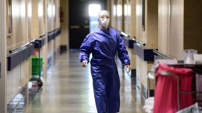Situasi penanganan virus corona di salah satu rumah sakti di Italia, dokter mengenakan alat pelindung diri lengkap dan masker. (PIERO CRUCIATTI / AFP)