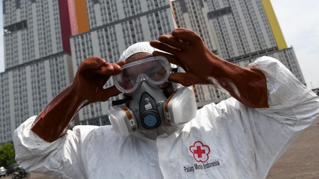 Petugas Palang Merah Indonesia (PMI) memakai kacamata pelindung untuk melakukan penyemprotan cairan disinfektan pada Wisma Atlet di Kemayoran, Jakarta, Sabtu (21/3). [ANTARA FOTO/M Risyal Hidayat]