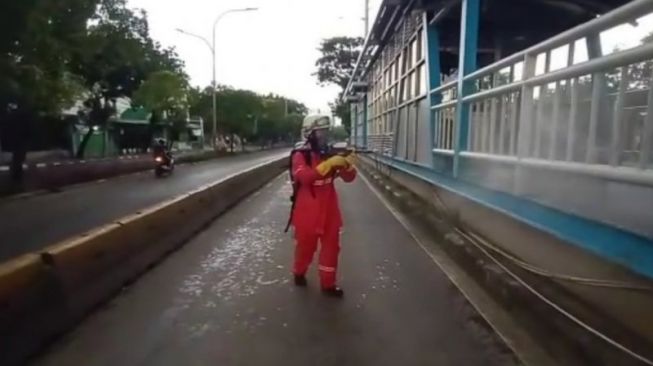 Petugas Pemadam Kebakaran (Damkar) Jakarta Timur menyemprotkan disinfektan di sepanjang jalan protokol di Jakarta, Minggu (22/3/2020). (Antara)