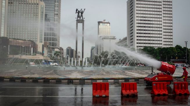 Petugas Damkar menyemprotkan cairan disinfektan di kawasan Bundaran HI, Jakarta, Minggu (22/3). [ANTARA FOTO/Aprillio Akbar]