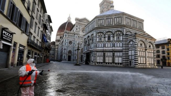 Seorang pekerja menyemprotkan cairan disinfektan di jalanan kawasan Piazza del Duomo, Kota Folorence, Italia. (Foto: AFP)