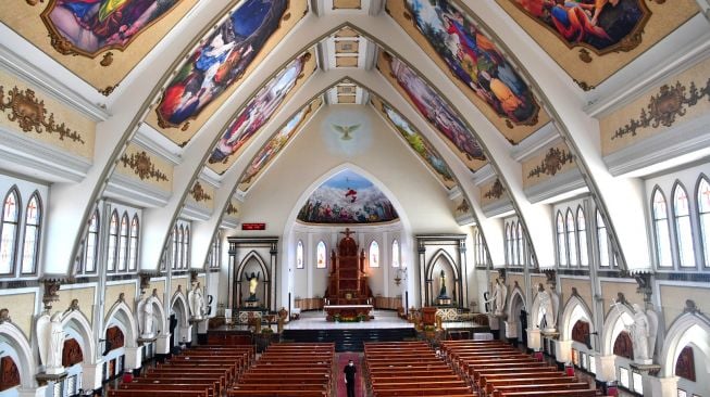 Petugas keamanan gereja melintas diantara kursi kosong di Gereja Katolik Santo Yakobus Surabaya, Jawa Timur, Minggu (22/3). [ANTARA FOTO/Zabur Karuru]