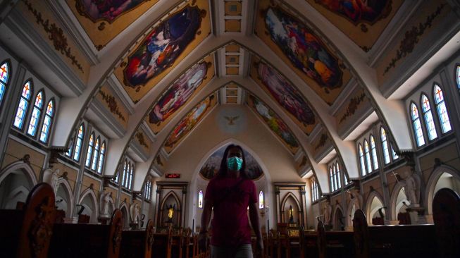 Petugas keamanan gereja melintas diantara kursi kosong di Gereja Katolik Santo Yakobus Surabaya, Jawa Timur, Minggu (22/3). [ANTARA FOTO/Zabur Karuru]