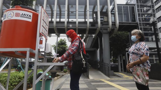 Warga mengantre untuk mencuci tangan di fasilitas tempat mencuci tangan untuk umum di kawasan Senayan, Jakarta, Senin (23/3). [Suara.com/Angga Budhiyanto]