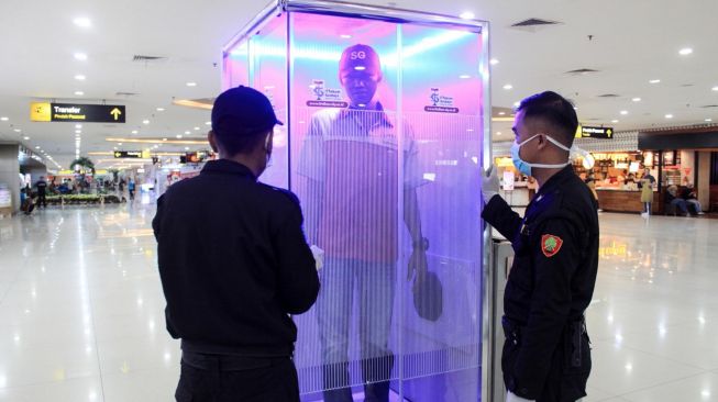 Penumpang diperiksa di ruang sterilisasi (Sterilization Chamber) yang terpasang di Terminal 2 Bandara Internasional Juanda di Sidoarjo, Jawa Timur, Minggu (22/3).  [ANTARA FOTO/Umarul Faruq]