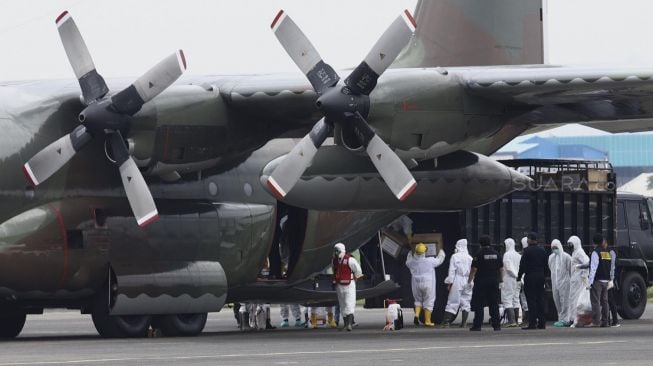 Petugas memindahkan muatan logistik kesehatan dari Pesawat Hercules C-130 saat mendarat di Landasan Udara (Lanud) Halim Perdanakusuma, Jakarta, Senin (23/3).[Suara.com/Angga Budhiyanto]