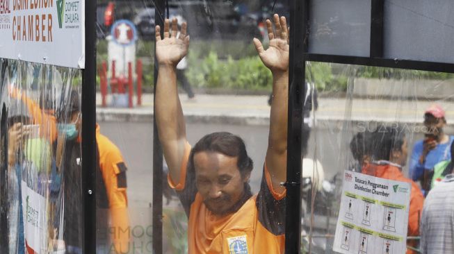 Petugas PPSU menjajal alat Disinfection Chamber di kawasan Blok M, Jakarta Selatan, Selasa (24/3). [Suara.com/Angga Budhiyanto]