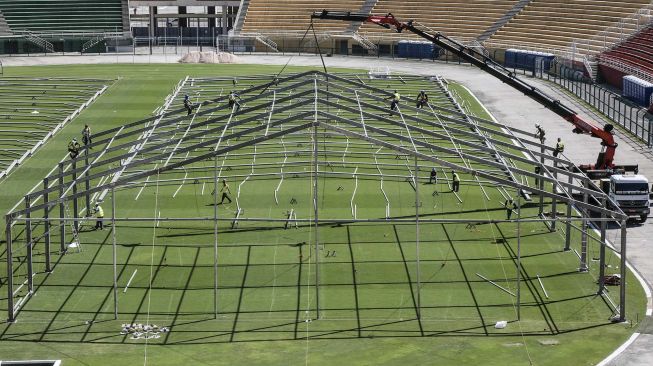 Pekerja membangun rumah sakit sementara di lapangan sepakbola untuk menampung pasien terinfeksi virus Corona COVID-19 di stadion Pacaembu, Sao Paolo, Brasil, Senin (23/3). [AFP/ Nelson Amneida]