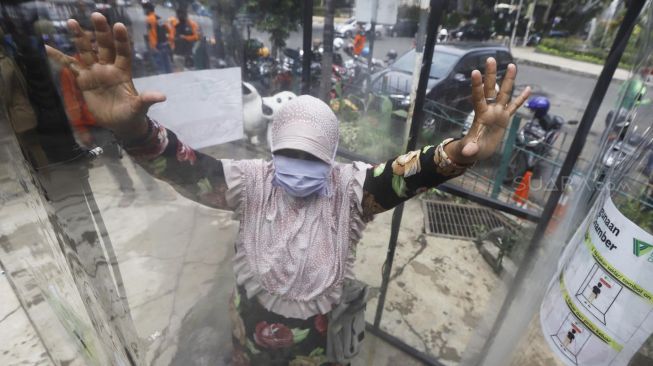 Warga menjajal alat Disinfection Chamber di kawasan Blok M, Jakarta Selatan, Selasa (24/3).  [Suara.com/Angga Budhiyanto]
