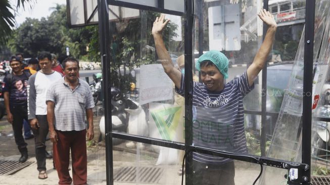 Warga mengantre untuk menjajal alat Disinfection Chamber di kawasan Blok M, Jakarta Selatan, Selasa (24/3). [Suara.com/Angga Budhiyanto]