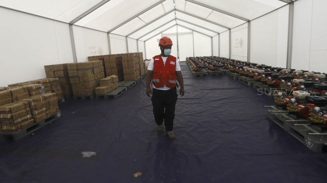 Petugas Palang Merah Indonesia (PMI) meninjau logistik kesehatan di Gudang Logistik Darurat Penanganan COVID-19 di Jalan Gatot Soebroto, Jakarta, Rabu (25/3).  [Suara.com/Angga Budhiyanto]   
